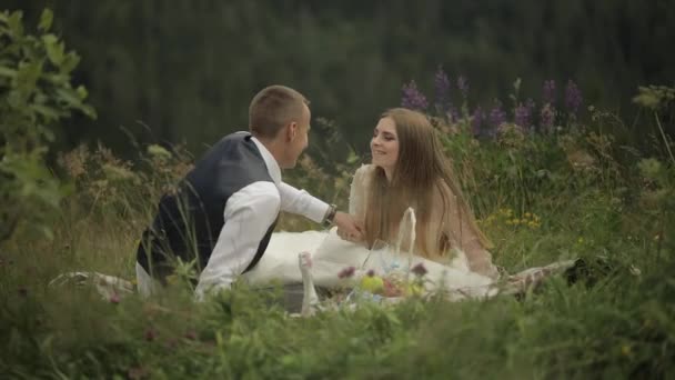 Brudgummen med bruden som har en picknick på ett berg kullar. Bröllopspar. Familj — Stockvideo