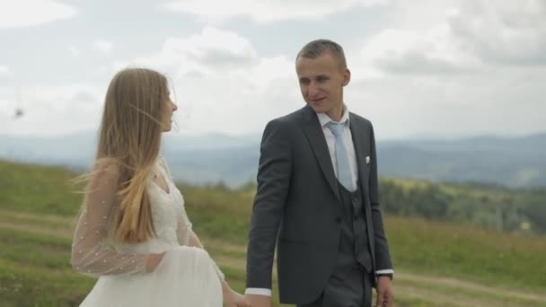 Vőlegény a menyasszony séta együtt a hegyi dombok. Nászpár — Stock videók