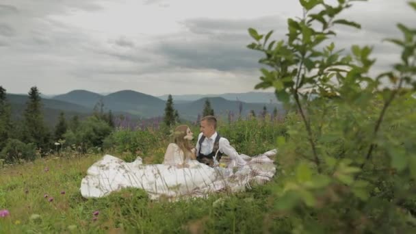 Brudgummen med bruden som har en picknick på ett berg kullar. Bröllopspar. Familj — Stockvideo