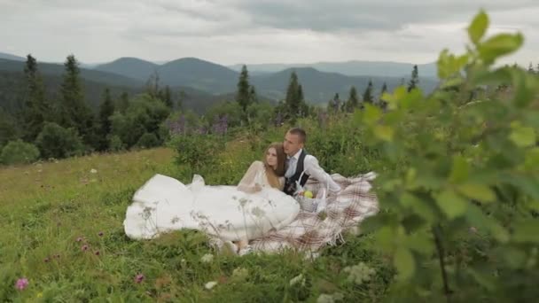 Brudgummen med bruden som har en picknick på ett berg kullar. Bröllopspar. Familj — Stockvideo