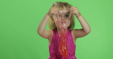 Çocuk kırmızı balçık yaparken eğleniyor. El yapımı oyuncak balçıkile oynayan çocuk