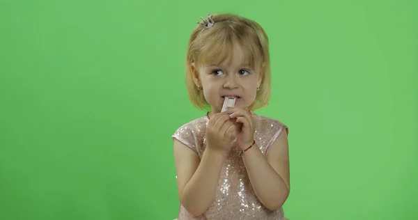 Menina em vestido brilhante começa a comer chiclete. Criança feliz. Chave Chroma — Fotografia de Stock