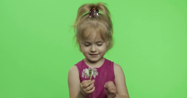 Dziewczyna trzyma kwiat rumianku i mówi coś. Szczęśliwego małego dziecka. Klucz chrominancji — Wideo stockowe