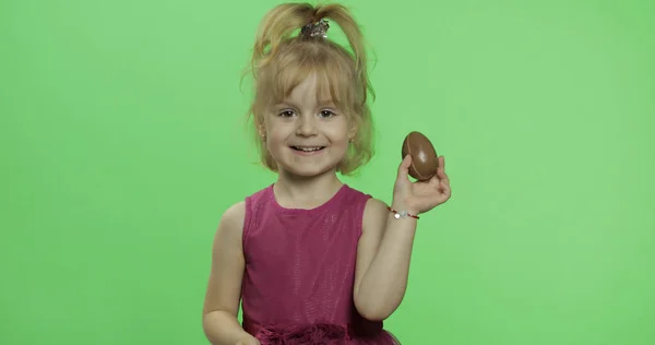 Dívka v purpurovém oblečení s čokoládovým vejcem. Šťastné čtyři roky staré dítě. Klíč Chroma — Stock fotografie
