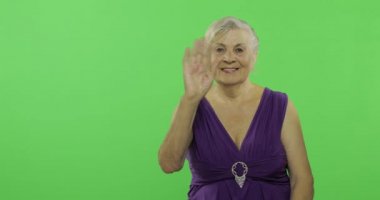 Yaşlı bir kadın kameraya sallayıp gülümsüyor. Yaşlı büyükanne. Chroma anahtarı