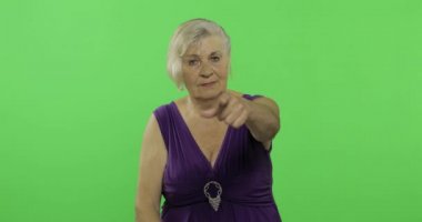 Yaşlı bir kadın kameraya işaret ediyor ve gülümsüyor. Yaşlı büyükanne. Chroma anahtarı