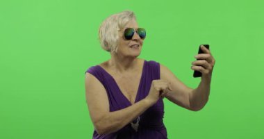Akıllı telefon kullanarak görüntülü sohbet sahip yaşlı bir kadın. Chroma anahtarı