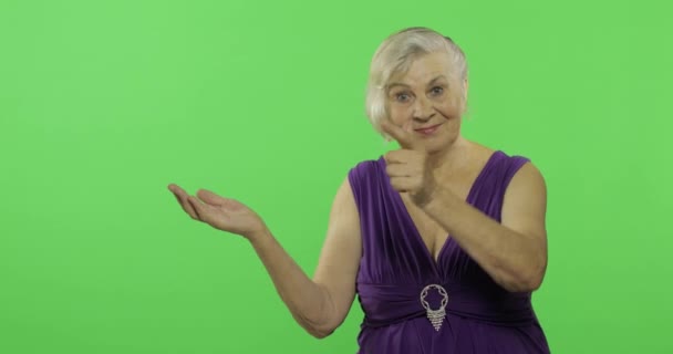 한 연로한 여성이 무언가를 가리키며 미소를 지었다. 할머니. 크로마 키 — 비디오