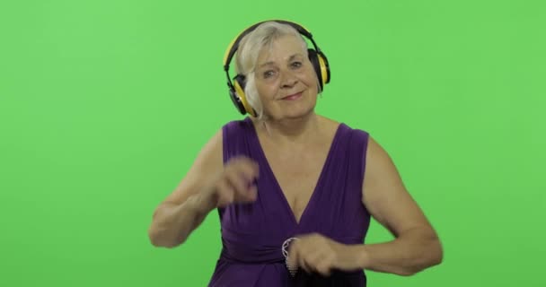 Starsza kobieta słucha muzyki w słuchawkach i tańce. Babcia. Klucz chrominancji — Wideo stockowe