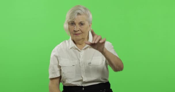 Eine ältere Frau zeigt in die Kamera und lächelt. alte Großmutter. Chroma-Schlüssel — Stockvideo
