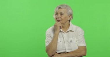 Yaşlı bir kadın bir şey düşünüyor. Eski düşünceli büyükanne. Chroma anahtarı