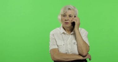 Bir akıllı telefonda yaşlı bir kadın konuşuyor. Yaşlı büyükanne gülümsüyor. Chroma anahtarı