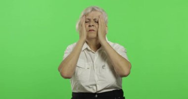 Yaşlı bir kadın baş ağrısı ağrı sorunu ile muzdarip. Yaşlı büyükanne. Chroma anahtarı