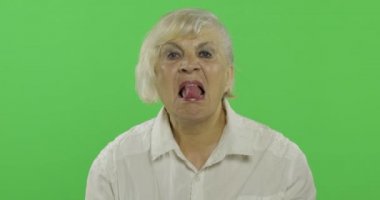 Yaşlı bir kadın dilini gösterir. Yaşlı, mutlu büyükanne. Chroma anahtarı