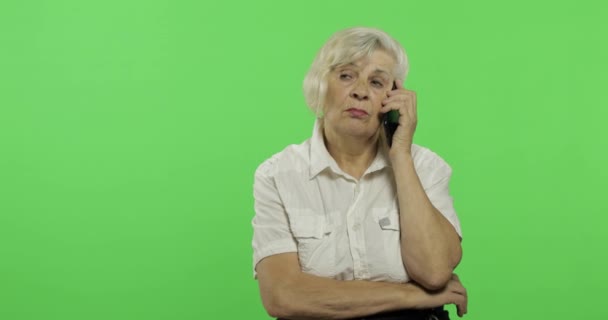 An elderly woman talks on a smartphone. Old grandmother smiles. Chroma key — Stock Video