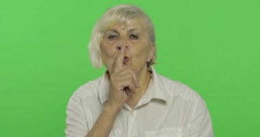 Yaşlı bir kadın sessiz jest gösteriyor. Yaşlı büyükanne. Chroma anahtarı