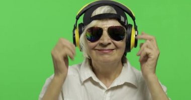 Yaşlı kadın kulaklıklar ve dans müzik dinler. Büyükanne. Chroma anahtarı