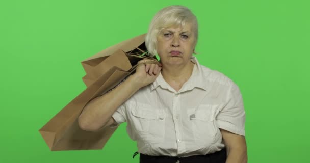 Μια ηλικιωμένη βαριεστημένη γυναίκα με σακούλες για ψώνια. Ψώνια. Παρουσιάζει. Πλήκτρο αποχρώσεων — Αρχείο Βίντεο