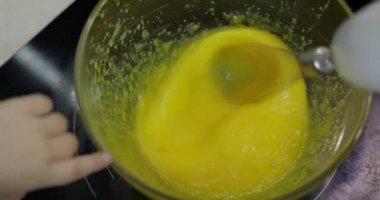 Kız bir cam kase şeker ile çiğ yumurta kamçı. Yumurta whisking