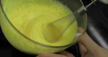 Kız bir cam kase şeker ile çiğ yumurta kamçı. Yumurta whisking