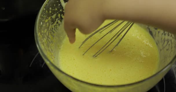 Barnhand tar med ett finger vispad råa ägg med socker i en glasskål — Stockvideo