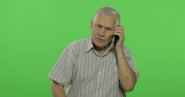 Bir akıllı telefonda kıdemli adam konuşuyor. Chroma anahtar arka planda yakışıklı yaşlı adam