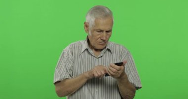 Kıdemli adam akıllı telefonda çalışıyor. Chroma anahtar arka planda yakışıklı yaşlı adam