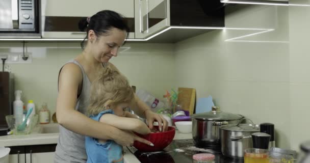 Madre e hija mezclando masa de chocolate, niña haciendo pastel en la cocina — Vídeos de Stock