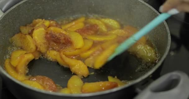 Персики, разрезанные на куски, карамелизируются в кастрюле с сахаром — стоковое видео
