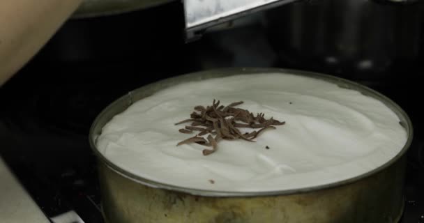 Подготовка чизкейка. Добавление шоколада на торт со сливками — стоковое видео