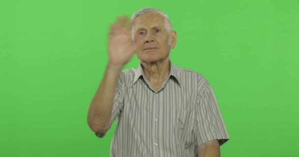 Starszy mężczyzna machając rękami do aparatu. Przystojny stary człowiek na Chroma klucz tło — Wideo stockowe