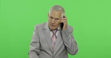Akıllı telefonda yakışıklı yaşlı işadamı görüşmeleri. Takım elbiseli yaşlı adam