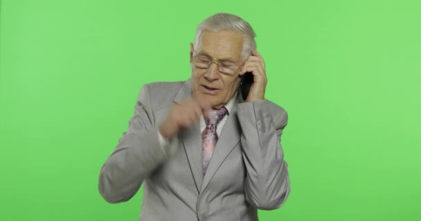 Handsome elderly businessman talks on a smartphone. Old man in suit — Stock Video