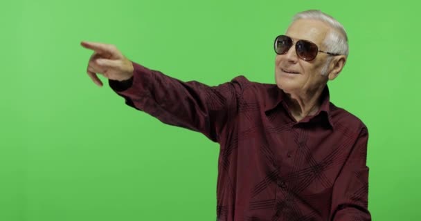 Hombre mayor turista en gafas de sol apunta a algo. Viejo guapo. — Vídeos de Stock