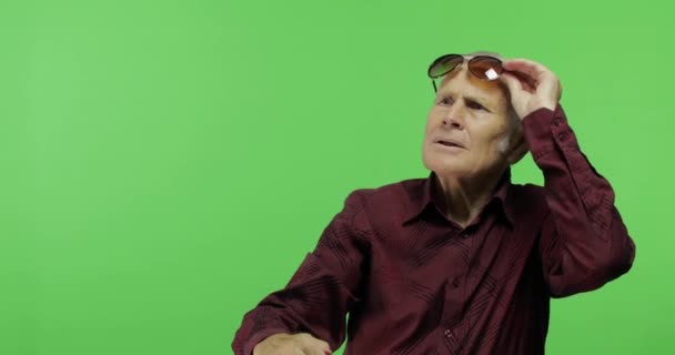 Ένας ανώτερος τουρίστας με γυαλιά ηλίου που κοιτάζει κάτι. Όμορφος γέρος άντρας — Αρχείο Βίντεο