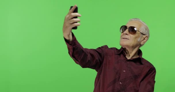 Hombre mayor turista en gafas de sol hacer una foto en un teléfono inteligente. Selfie. — Vídeos de Stock