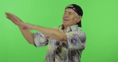 Renkli gömlek dansları kıdemli adam turist. Yakışıklı eski adam üzerinde Chroma anahtar