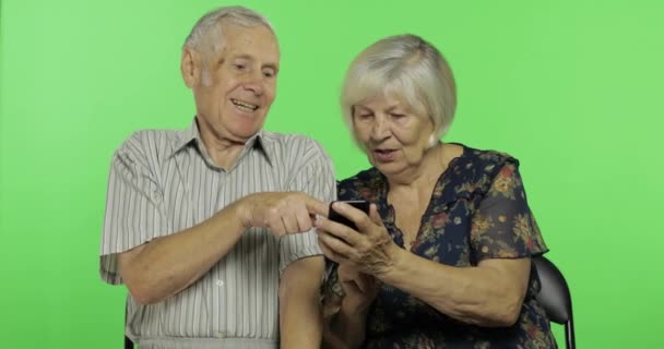 Homem e mulher idosos idosos sentados juntos e trabalhando em smartphones. Chave Chroma — Vídeo de Stock