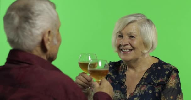 Senior aged woman drinking wine with a elderly man companion on chroma key — Stock Video