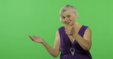 Yaşlı bir kadın bir şeyi işaret ediyor ve gülümsüyor. Yaşlı büyükanne. Chroma anahtarı