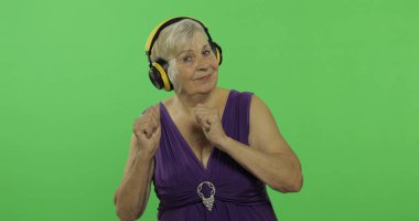 Yaşlı kadın kulaklıklar ve dans müzik dinler. Büyükanne. Chroma anahtarı