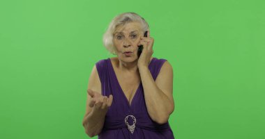 Bir akıllı telefonda yaşlı bir kadın konuşuyor. Yaşlı büyükanne gülümsüyor. Chroma anahtarı