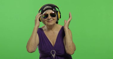 Yaşlı kadın kulaklıklar ve dans müzik dinler. Büyükanne. Chroma anahtarı