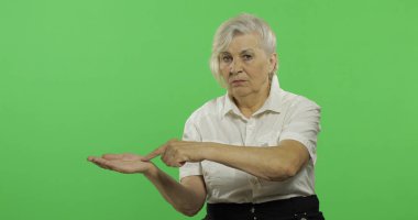 Yaşlı bir kadın bir şeyi işaret ediyor ve gülümsüyor. Yaşlı büyükanne. Chroma anahtarı