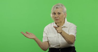 Yaşlı bir kadın kameraya işaret ediyor ve gülümsüyor. Yaşlı büyükanne. Chroma anahtarı
