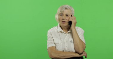 Bir akıllı telefonda yaşlı bir kadın konuşuyor. Yaşlı büyükanne gülümsüyor. Chroma anahtarı