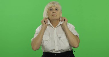 Yaşlı bir kadın elbiselerini ayarlar ve gülümsüyor. Chroma anahtarı