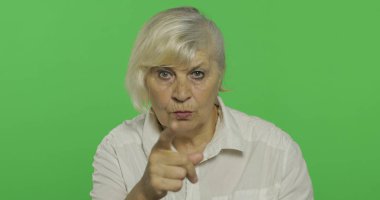 Yaşlı bir kadın kameraya işaret ediyor ve gülümsüyor. Yaşlı büyükanne. Chroma anahtarı