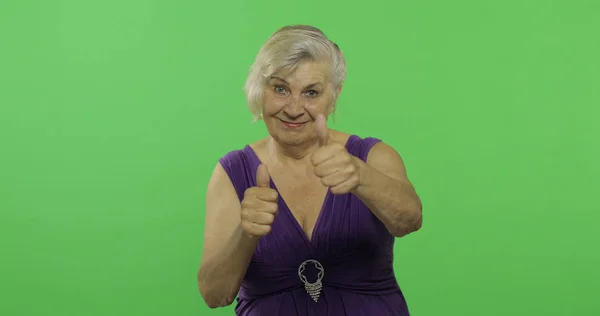 Una anciana muestra el pulgar hacia arriba y sonríe. Vieja abuela. Clave de croma — Foto de Stock