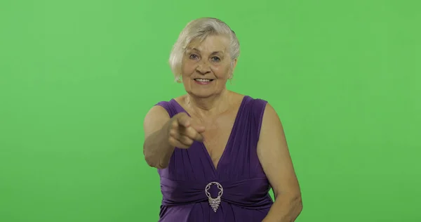 Starsza kobieta wskazuje na aparat i uśmiechy. Stara babcia. Klucz chrominancji — Zdjęcie stockowe